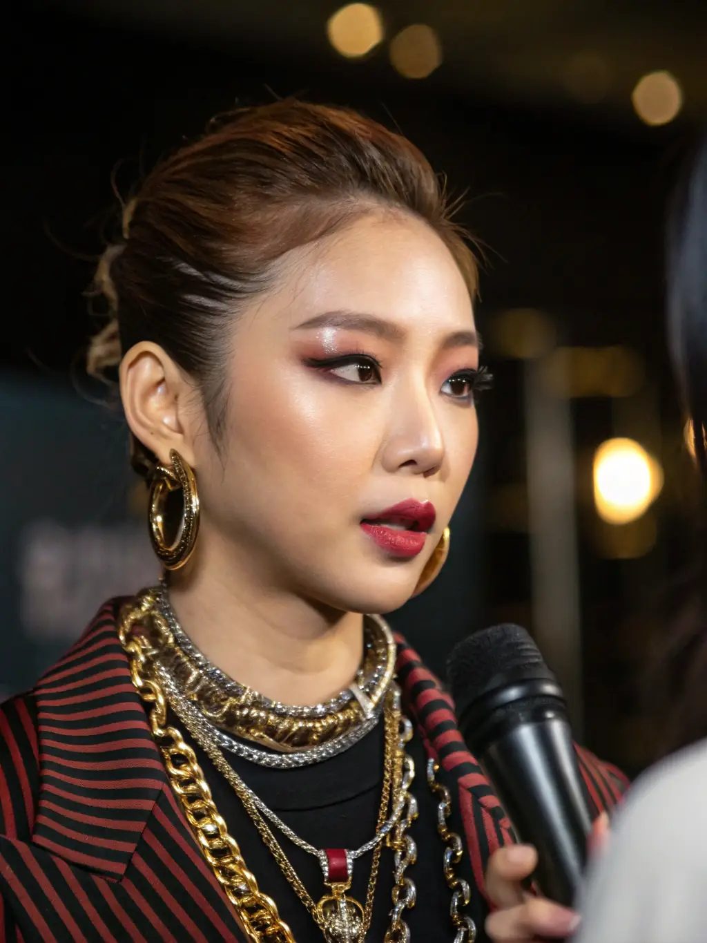 A close-up image of a renowned Korean stylist during an interview, showcasing their unique accessories and fashion sense.