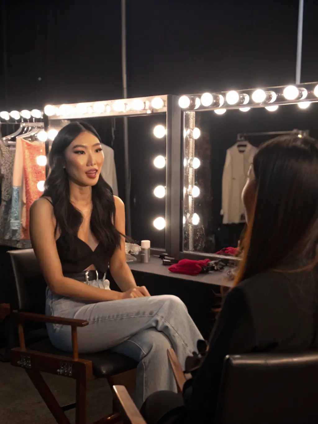 A candid shot of a Korean supermodel backstage during an interview, discussing her experiences and beauty secrets.